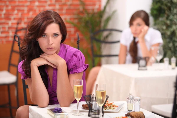 Angry woman at the restaurant, on the table, an unopened gift and flutes o — Stock Photo, Image