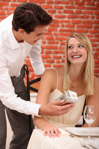 Couple with a present in a restaurant — Stock Photo, Image