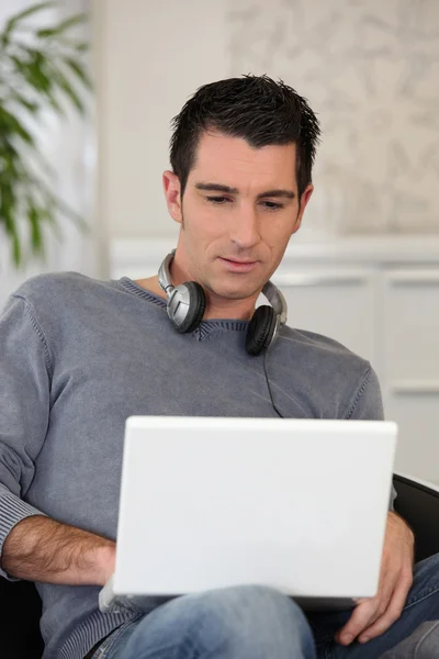 Az ember egy laptop számítógép használata közben a fejhallgató viselése — Stock Fotó