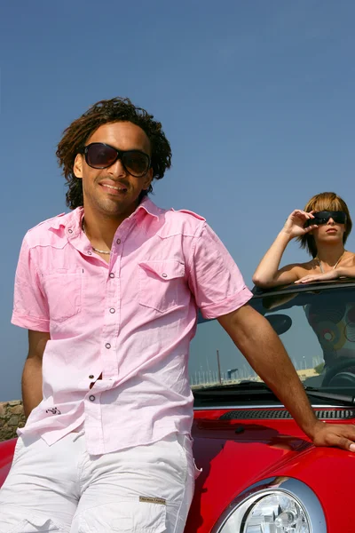 Guy showing off near roadster with pretty girl — Stock Photo, Image