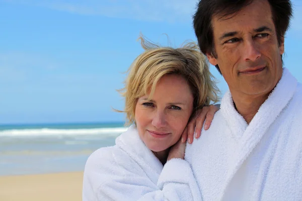 Couple in robes on the beach — Stockfoto