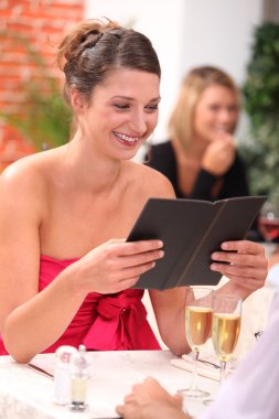 Woman looking at the menu at a restaurant clipart