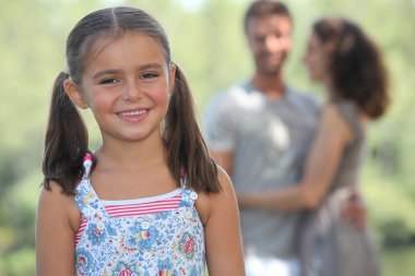 Young girl strolling in the park with her parents clipart