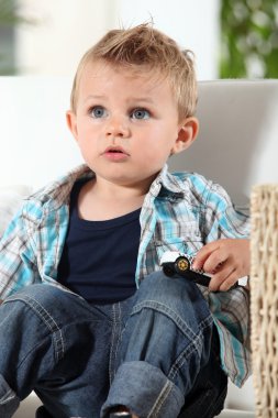 Little boy watching television with a toy car clipart