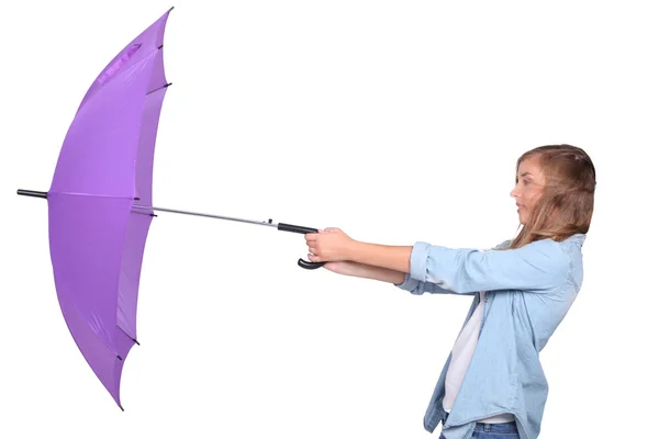 Junge Frau kämpft an einem windigen Tag mit einem lila Regenschirm — Stockfoto