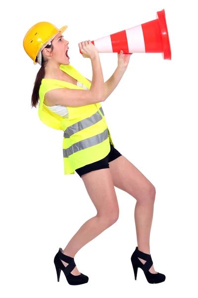 Mulher sexy vestida como construtor gritando em um cone de tráfego — Fotografia de Stock