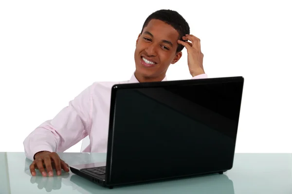 Jovem empresário sorridente em um laptop — Fotografia de Stock