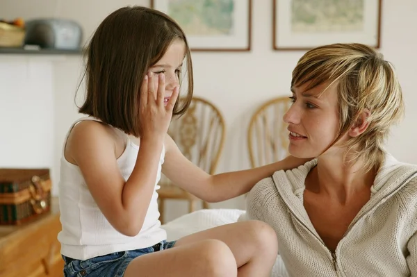 Little girl whispering secrets to her mom