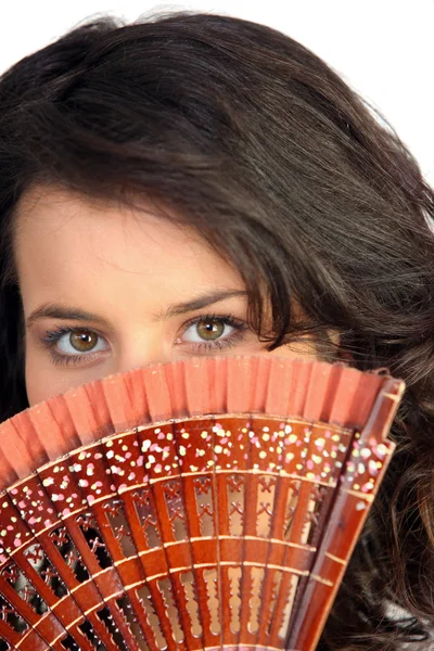 Close-up van een mooie vrouw verstopt achter een fan — Stockfoto