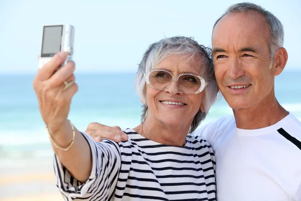 老夫妇在沙滩上考虑他们自己的照片 — 图库照片