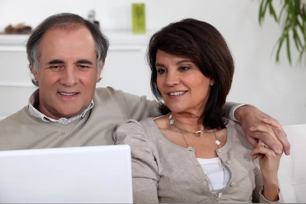 Ouder paar zittend op de Bank met laptop — Stockfoto