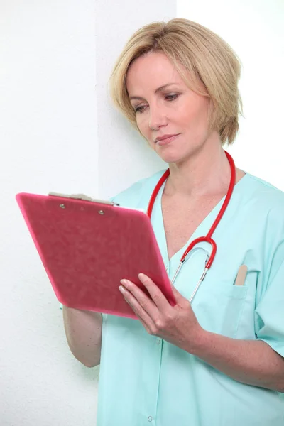 Una doctora tomando notas en un portapapeles . —  Fotos de Stock