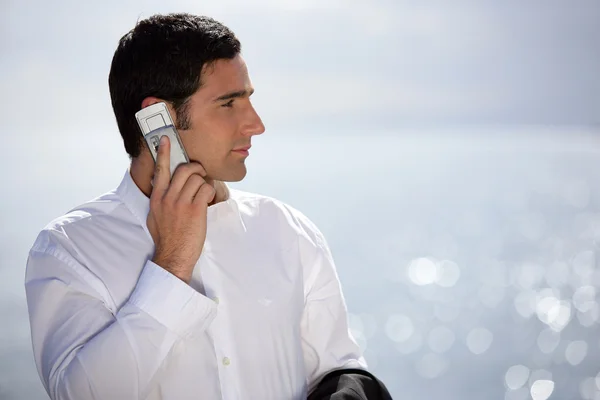 Young man in suit with a phone near the sea — Stock Photo, Image