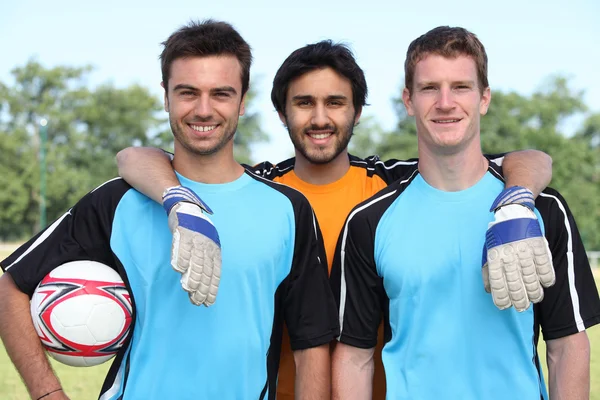 Três futebolistas sorridentes com bola — Fotografia de Stock
