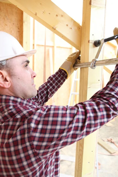 Costruttore utilizzando un morsetto per fissare due assi di legno insieme — Foto Stock