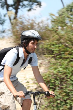 Action shot of man riding bike through forest clipart