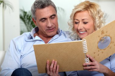 Smiling man and woman watching a photo album clipart