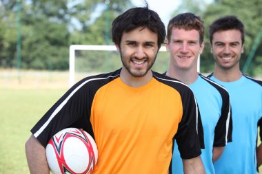 Three footballers in a line-up in front of goal clipart