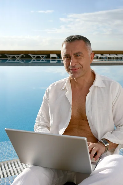 Man med datorn vid poolen — Stockfoto