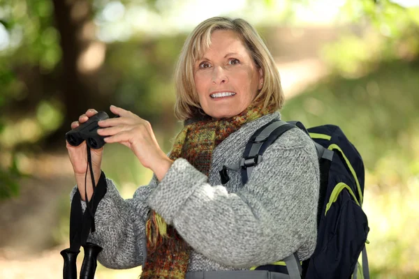 Blonde oudere vrouw met een verrekijker — Stockfoto