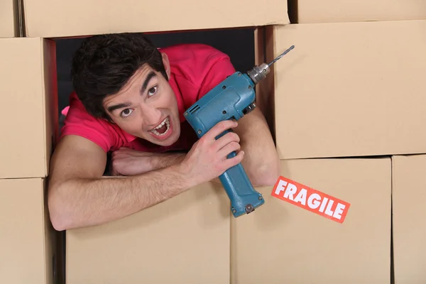 Homem com broca entre caixas — Fotografia de Stock