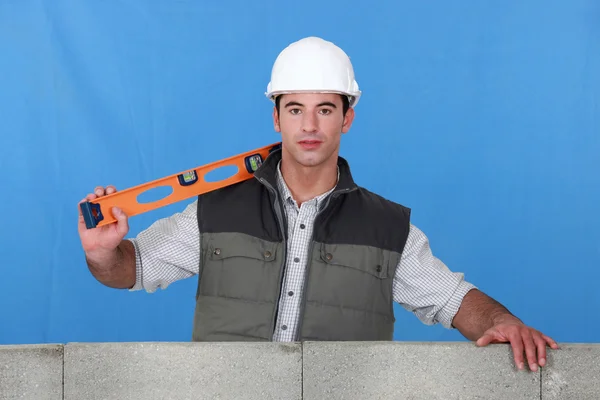 Man stood by wall with spirit-level — Stock Photo, Image