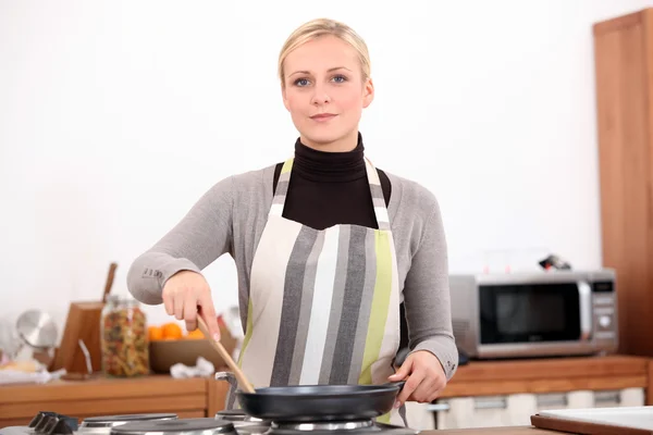 Mujer rubia de 30 años está cocinando con una estufa y una espátula en su kitc —  Fotos de Stock