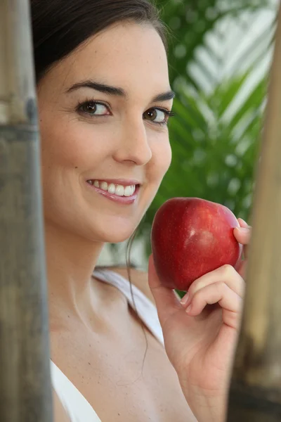 Γυναίκα τρώει ένα κόκκινο μήλο μεταξύ μπαμπού — Φωτογραφία Αρχείου
