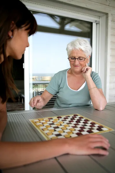 Молодая женщина и пожилая женщина играют в шашки — стоковое фото