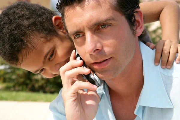 Junge umarmt seinen Vater, während er in seiner Zelle spricht — Stockfoto