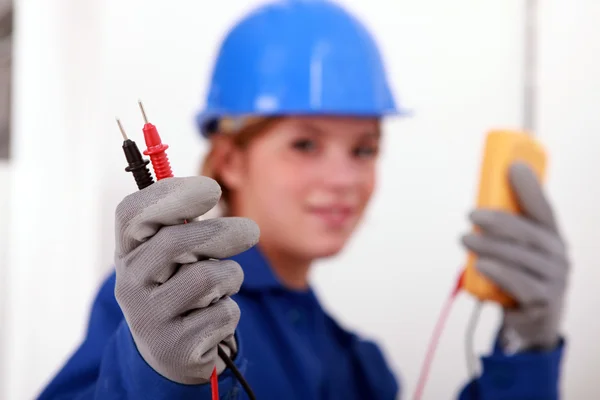 Een vrouwelijke elektricien houden een voltmeter. — Stockfoto