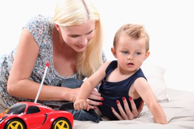 Young mother with her son and a remote controlled car clipart