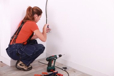 Young woman installing electricity in a house clipart