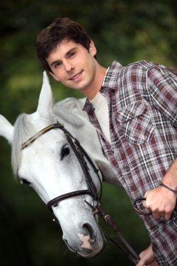 Closeup of young man with a white horse clipart