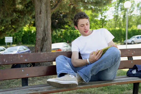 Adolescente lendo em um banco de parque — Fotografia de Stock