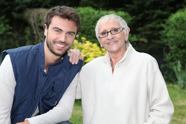 Lachende jonge man en oudere vrouw in tuin — Stockfoto