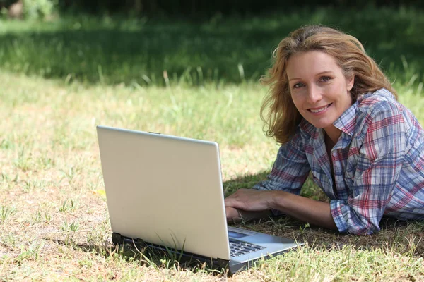 Женщина с ноутбуком на траве — стоковое фото