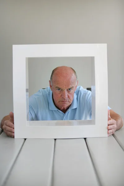 Uomo anziano guardando attraverso una cornice — Foto Stock