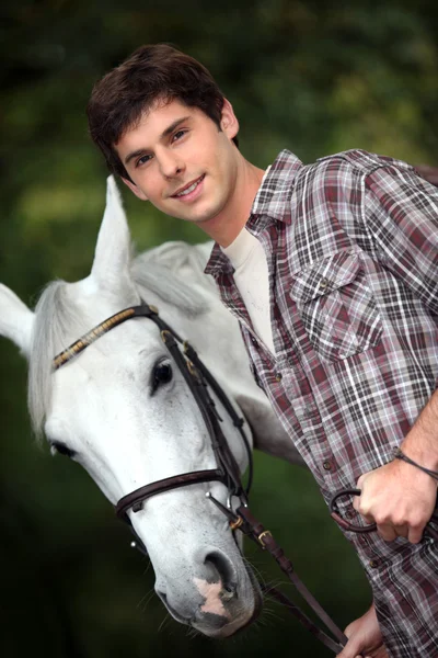 Närbild av ung man med en vit häst — Stockfoto
