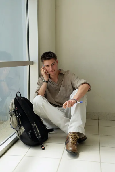 Ung man satt i korridoren att göra telefonsamtal — Stockfoto