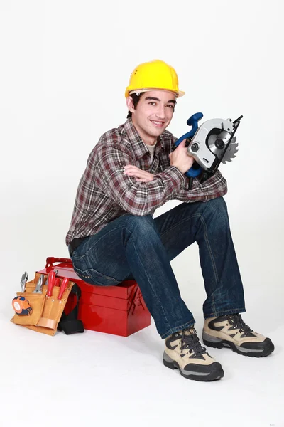 Carpinteiro sentou-se na caixa de ferramentas com serra circular elétrica — Fotografia de Stock