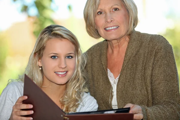 Senior a její vnučka, při pohledu na fotografie — Stock fotografie