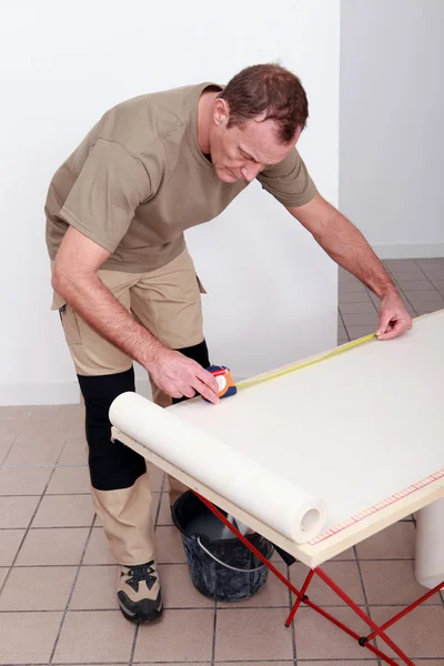 Decorador medindo um rolo de papel de parede — Fotografia de Stock