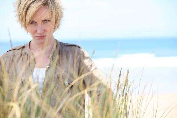 Femme blonde avec une expression sérieuse à la plage — Photo