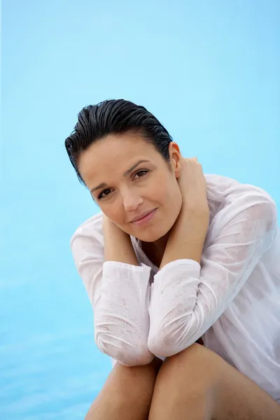 Bruna seduta a bordo piscina in camicia bagnata — Foto Stock