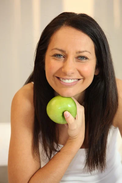 Retrato de uma mulher sorridente com uma maçã Granny Smith — Fotografia de Stock
