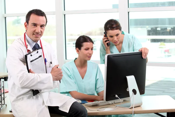Three doctors gathered around desk — Stock Photo, Image