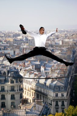 Businessman jumping for joy on a tightrope clipart