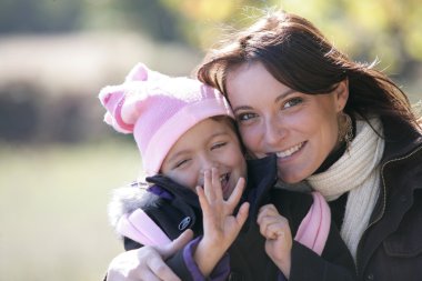 Mother and daughter outside on a sunny winter's day clipart