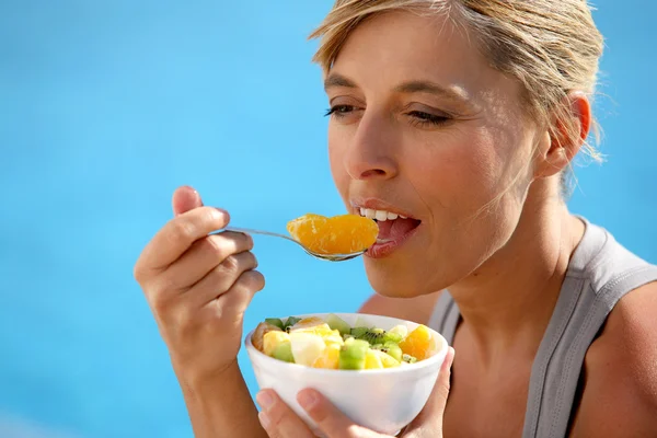 Kvinna äta en fruktsallad vid poolen — Stockfoto